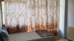 Ein Schlafzimmer mit einem Bett, einer Bank und einem Fenster mit Vorhängen.