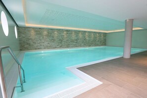 Ein Schwimmbecken mit gefliestem Boden und einer Wand mit strukturierter Oberfläche.