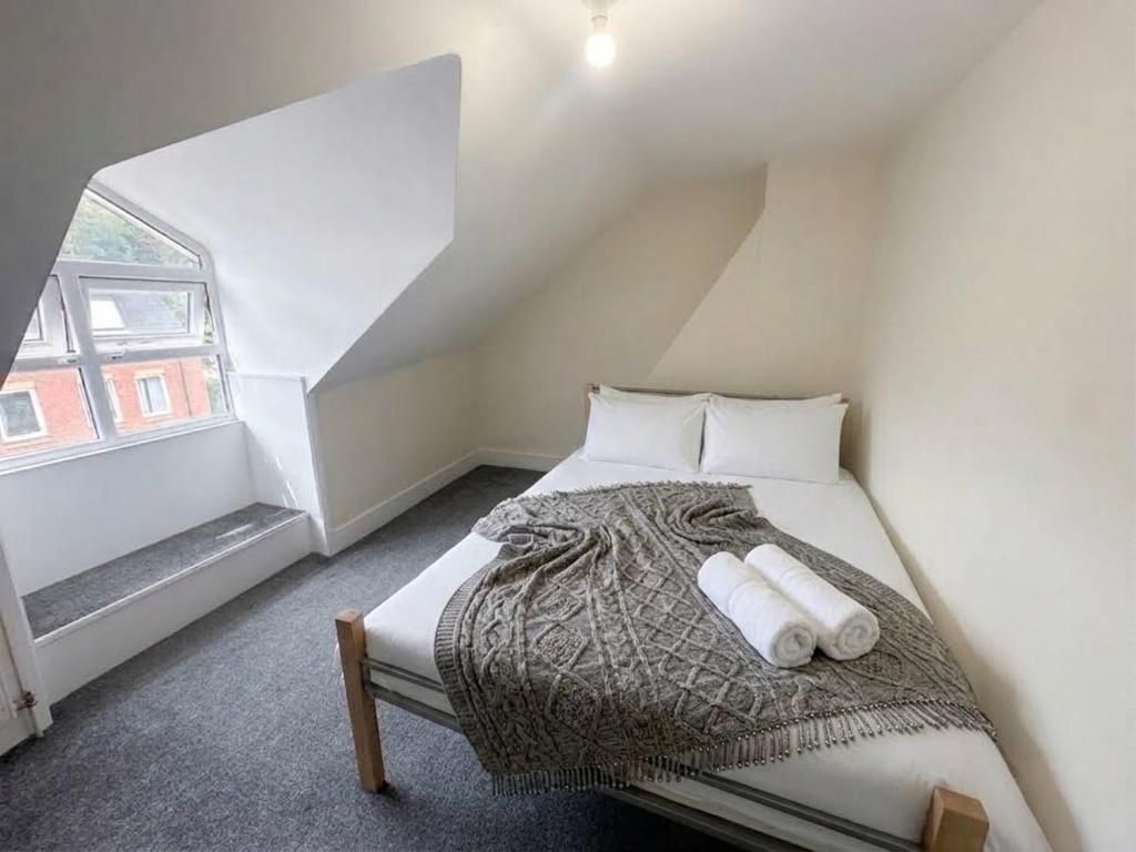 A bedroom with a sloped ceiling, a bed with a patterned blanket, and a window overlooking a building.