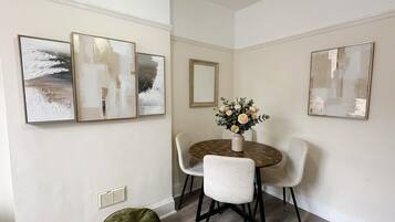 A dining area with a round table, four chairs, and three wall-mounted abstract paintings.