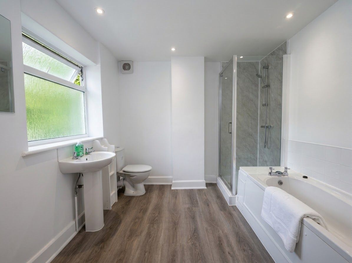 A modern bathroom with a shower, toilet, sink, and bathtub.