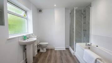 A modern bathroom with a shower, toilet, sink, and bathtub.