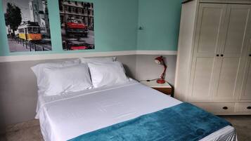 A bedroom with a bed, a nightstand, a lamp, a wardrobe, and two wall-mounted pictures.