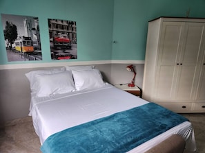 A bedroom with a bed, a nightstand, a lamp, a wardrobe, and two wall-mounted pictures. - Casa Mallorca Spacious Family Retreat in Cartagena de Indias (Cartagena)