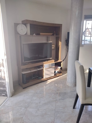 A living room with a flat-screen TV, wooden entertainment unit, and a chair. - Casa Mallorca Spacious Family Retreat in Cartagena de Indias (Cartagena)