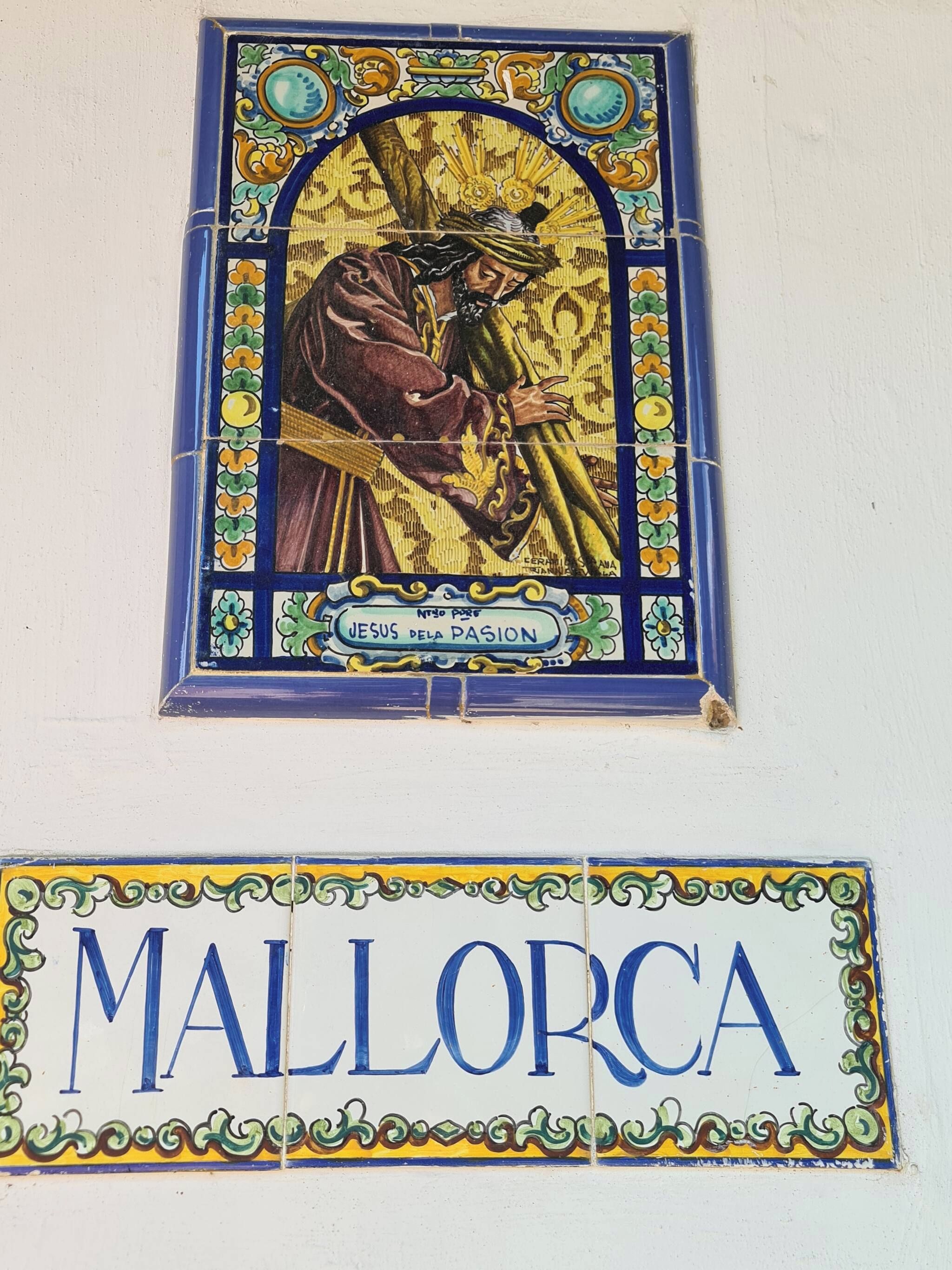 Vitrais com a figura de alguém e a inscrição 'JESUS FLETA PASCION', acompanhada de uma placa com a palavra 'MALLORCA'.