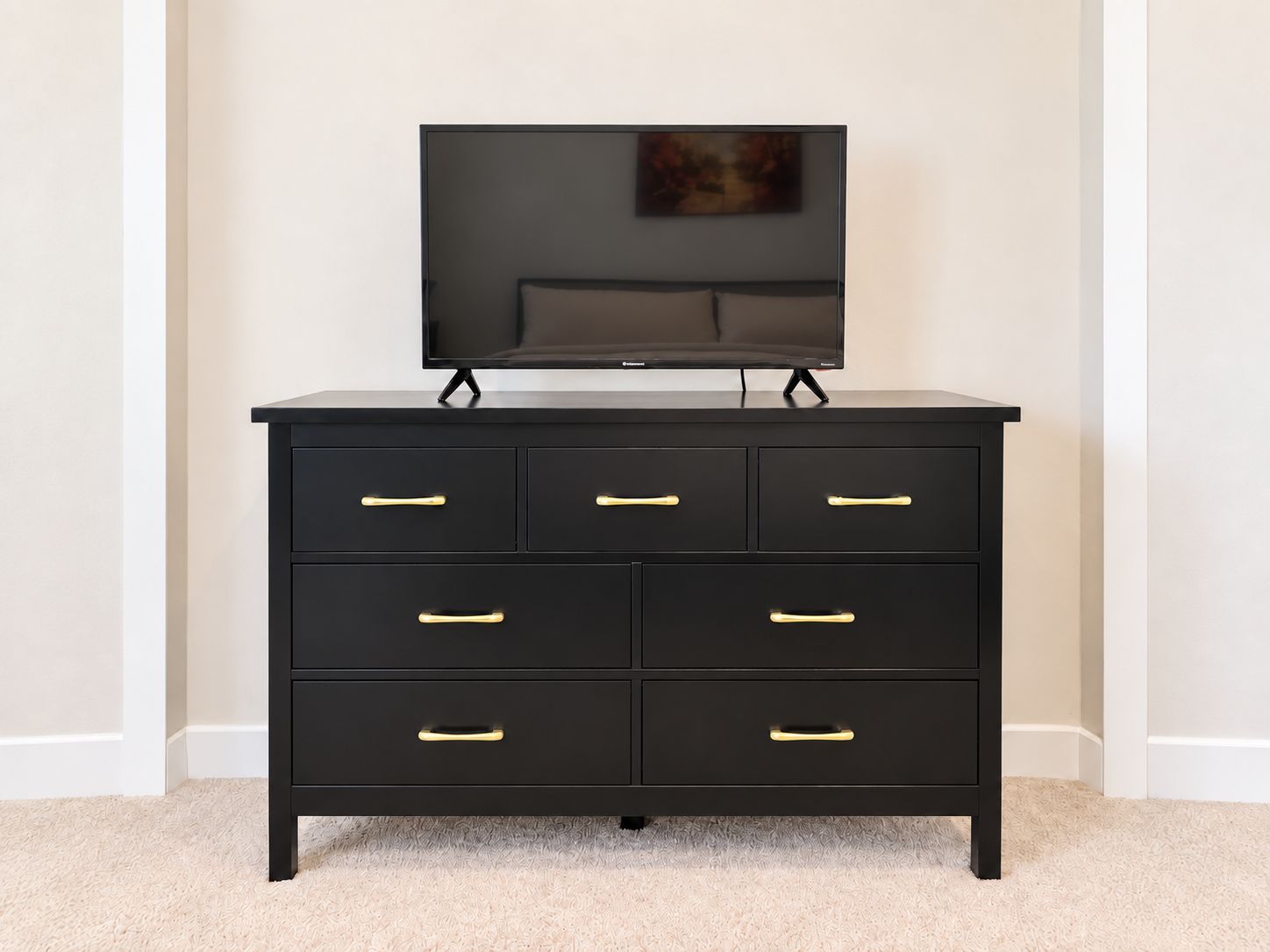 A black dresser with six drawers and a television on top.