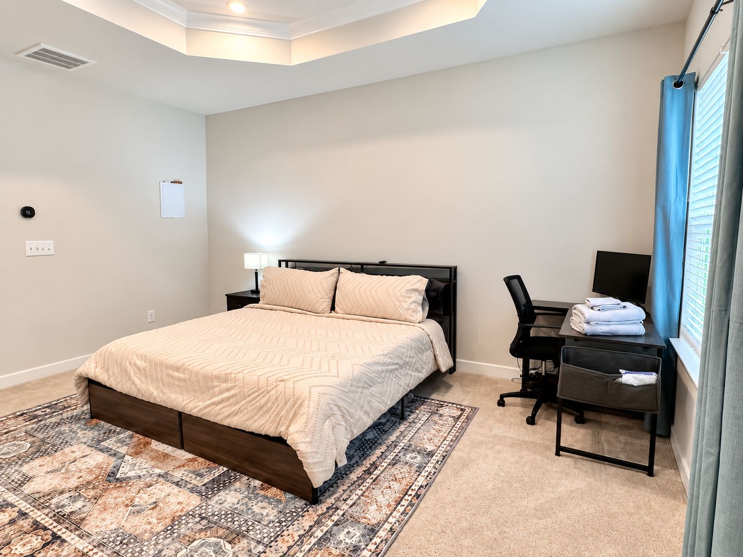 A bedroom with a bed, a desk, a chair, and a TV.