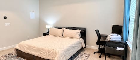 Un dormitorio con cama, escritorio, silla y televisor.