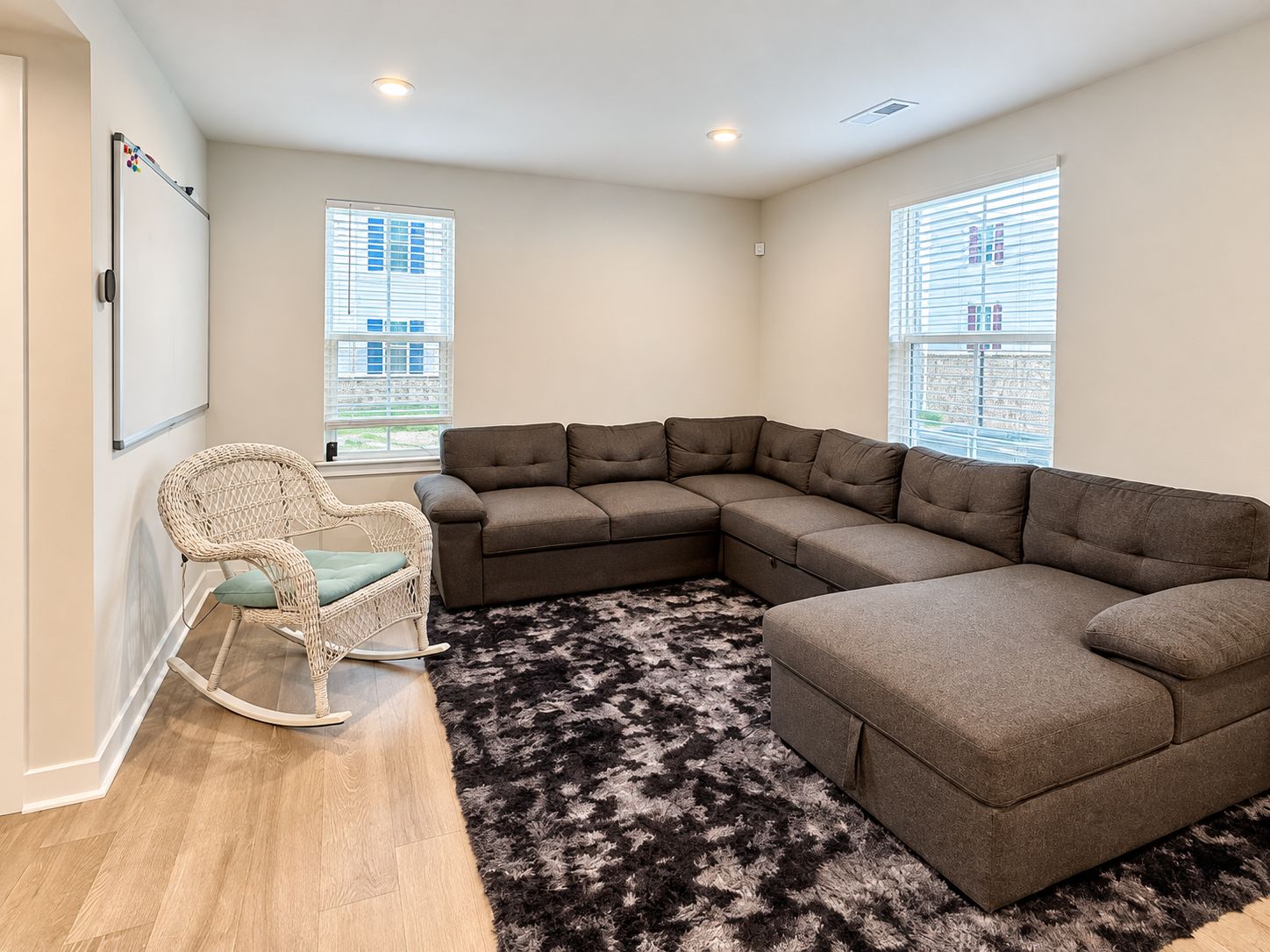 A living room with a sectional sofa, a rocking chair, and a patterned rug.