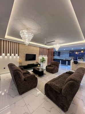 Ein modernes Wohnzimmer mit Flachbildfernseher, zwei Sofas, einem Couchtisch und einer Kandelaberleuchte.