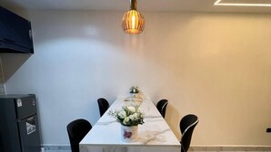 Ett modernt kök med en bänkskiva i marmor, en hängande taklampa och ett kylskåp.