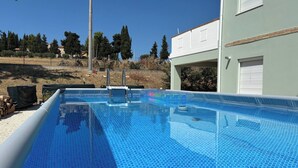 Une piscine à l’eau d’un bleu limpide, entourée d’une clôture et d’arbres.