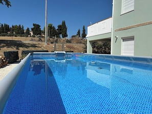 Una piscina con superficie azul cristalina, rodeada por una valla y árboles.