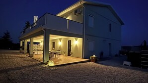 Une maison à deux étages dotée d’un patio couvert et d’un petit jardin.
