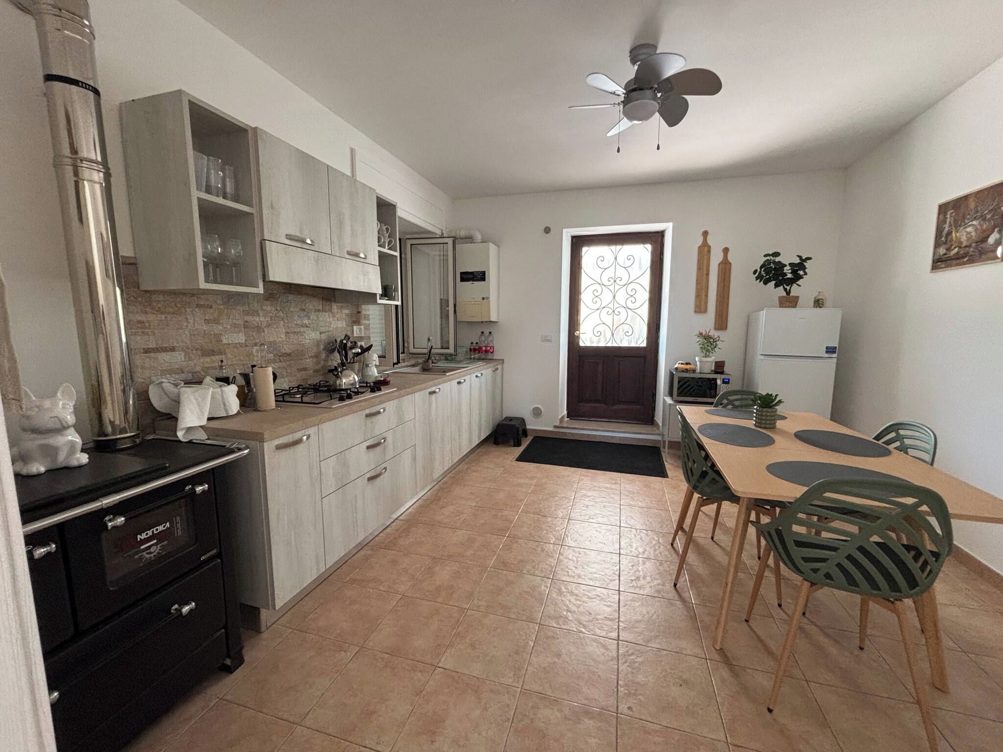 A kitchen with a dining area, a ceiling fan, and a refrigerator.