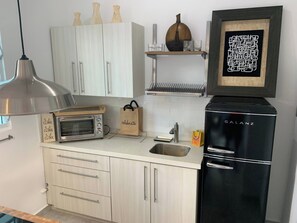 Eine Küche mit Einbauofen, Kühlschrank, Spüle und Pendelleuchte.