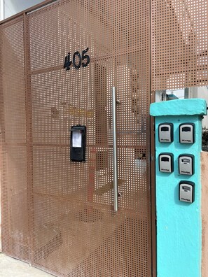 Ein Metallzaun mit der Nummer 405 und einem Keypad mit mehreren Tasten, vermutlich zur Zutrittskontrolle.