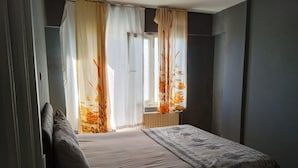Een slaapkamer met een bed, gordijnen en een raam.
