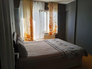 Un dormitorio con cama, cortinas y ventana.