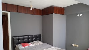 Een slaapkamer met een bed, een kledingkast en een stopcontact.