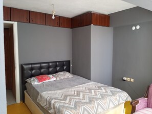 Un dormitorio con una cama, un armario y un enchufe.