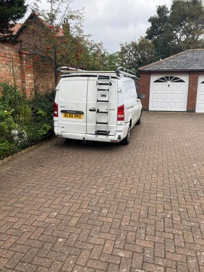 A white van parked in a driveway with a brick wall and a garage door in the background. - Beach Flat in Blundellsands, availble again (Blundellsands)