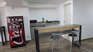 A kitchenette with a microwave, sink, and a Coca-Cola vending machine. - Modern Loft King Bed, Wifi & Smart Lock (Mexico City)