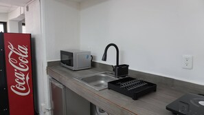 A kitchenette with a microwave, a sink, and a black faucet. - Modern Loft King Bed, Wifi & Smart Lock (Mexico City)