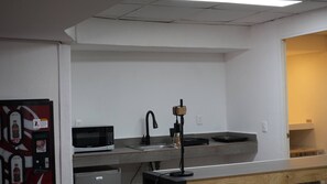 A kitchenette with a microwave, a sink, and a small refrigerator. - Modern Loft King Bed, Wifi & Smart Lock (Mexico City)