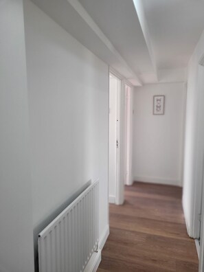 A hallway with white walls, a radiator, and a wooden floor. - Bright and Spacious 2 Bedroom Apartment Nr, Tower and London Bridge (London)