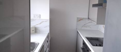 A compact kitchen with a washing machine, a sink, and a refrigerator.
