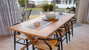 Un tavolo da pranzo in legno con una ciotola e un sottotavolo intrecciato, circondato da sedie con struttura in metallo nero.
