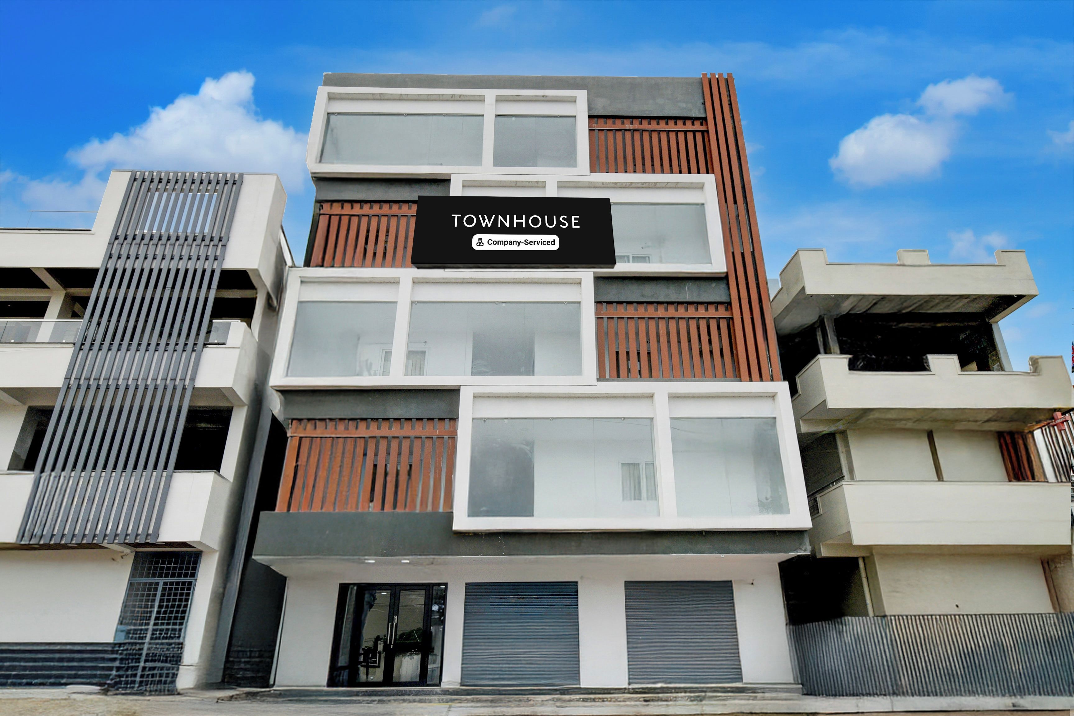 Un edificio de varios pisos con un letrero que dice 'TOWNHOUSE Company-Serviced'.