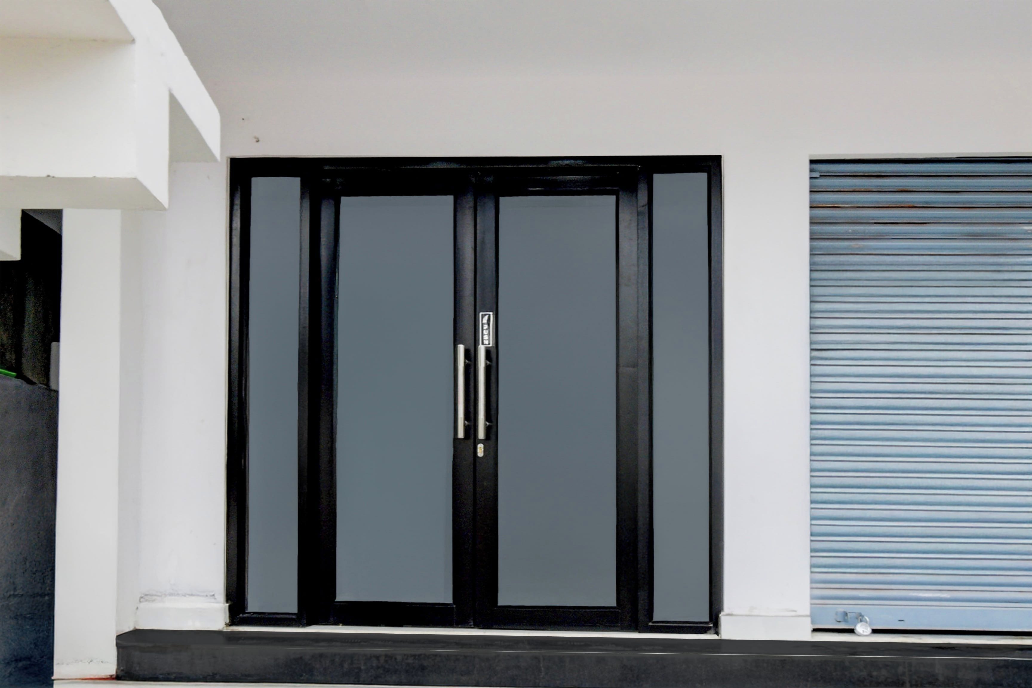 Eine moderne, schwarze Tür mit Griff, neben einer weißen Wand und einem blauen Rollo.