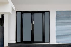 A modern black door with a handle, flanked by a white wall and a blue roller shutter. - Townhouse B N Reddy Capitol Stay Inn (Hyderabad)