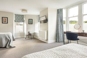 A bedroom with a bed, a desk, a chair, a radiator, and a window with curtains. - Family Room Near Windermere (Ambleside)