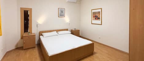 Ein Schlafzimmer mit einem hölzernen Bett, einem Nachttisch, einer Kommode und einem Kleiderschrank.