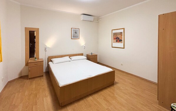 Une chambre à coucher avec un lit en bois, une table de chevet, une commode et une armoire.
