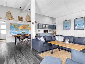 Ein modernes Interieur mit Essbereich, einer Sofagarnitur, einem Holztisch und einer Küche.
