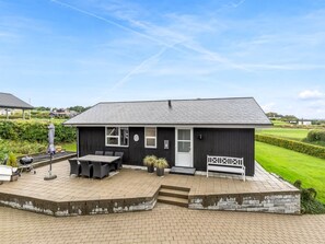 Ein modernes Haus mit einer Terrasse, einem Grill und einer weißen Bank.