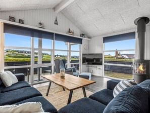Ein modernes Wohnzimmer mit Kamin, großen Fenstern und Blick auf die Landschaft.
