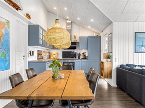 Ett modernt kök med matplats, med ett träbord, stolar och en hängande lampa.