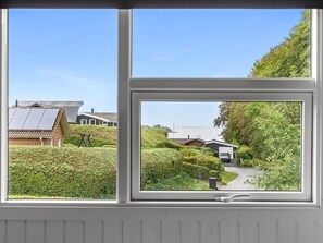 Blick aus dem Fenster auf eine Wohngegend mit Häusern, einem Weg und Grünflächen.