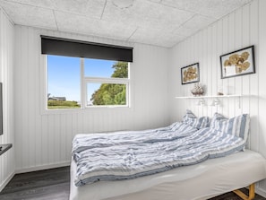 Ein Schlafzimmer mit einem Bett, einem Fenster und zwei Wandregalen mit Dekoration.