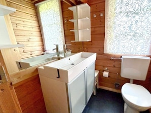 A wooden cabin bathroom with a white sink, mirror, and toilet. - Holiday Home Neckar 58 (Hayingen)