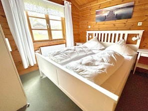 A wooden-paneled room with a bed, a window with curtains, and a wall-mounted picture. - Holiday Home Neckar 58 (Hayingen)