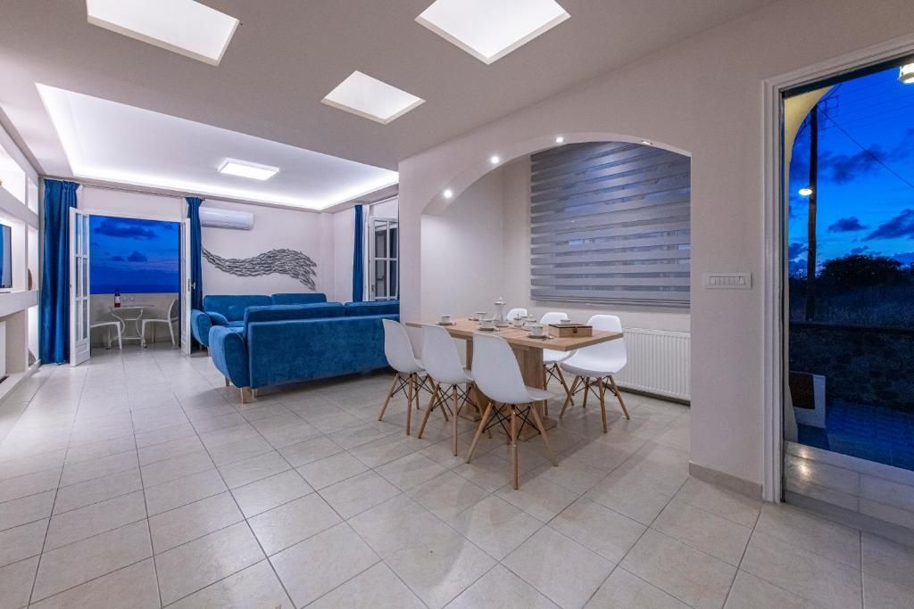 A modern interior with a dining area, a blue sofa, and a view through a glass door.