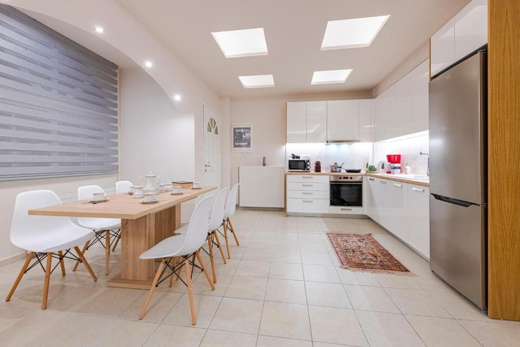 Cocina moderna con comedor, que incluye una mesa y sillas de madera, armarios blancos y un refrigerador de acero inoxidable.