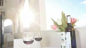 Ett bord med en flaska och två glas rött vin, en vas med blommor och en utsikt över himlen.